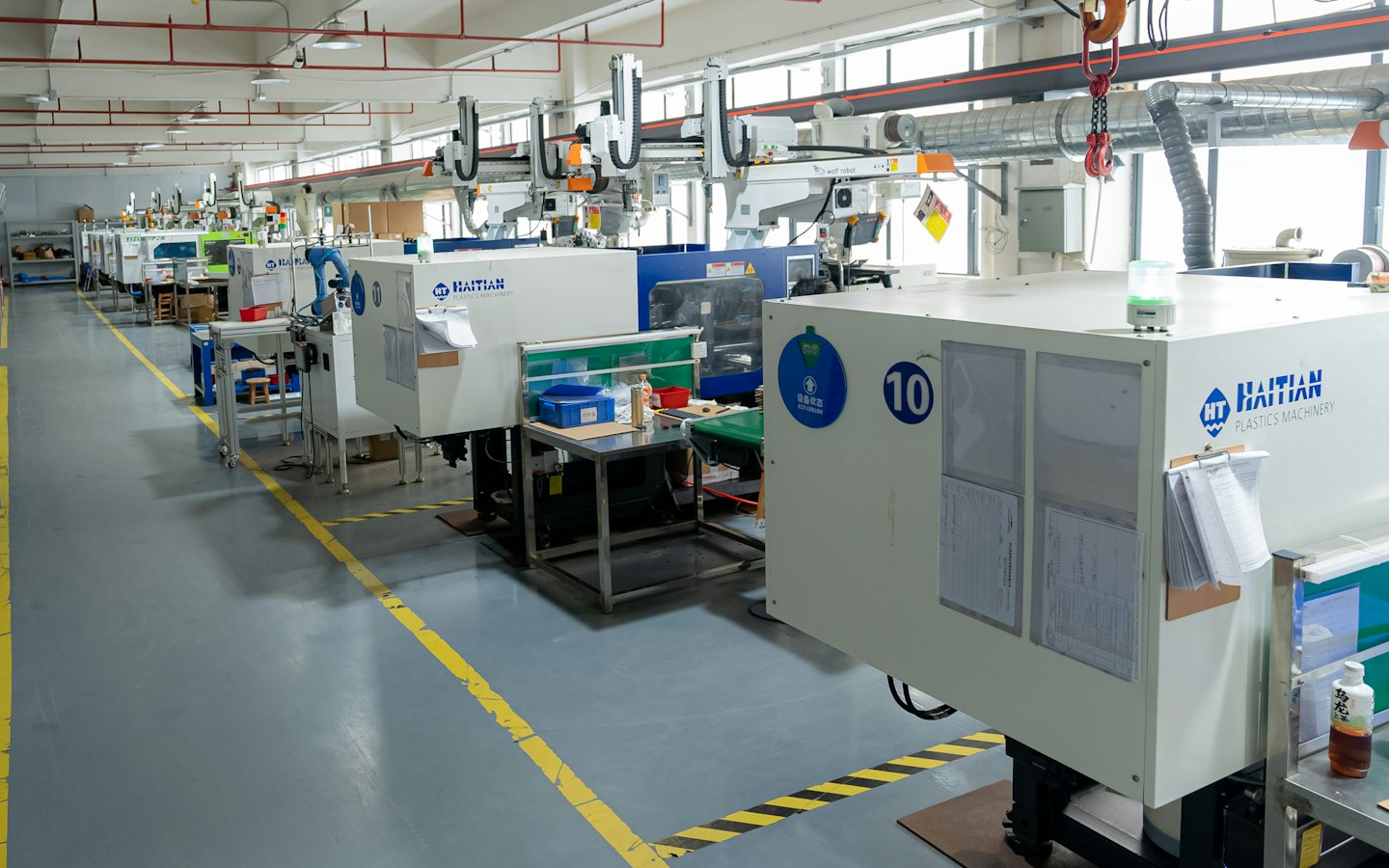 Fabrikada plastik enjeksiyon makinelerinde robotik kollar çalışıyor.